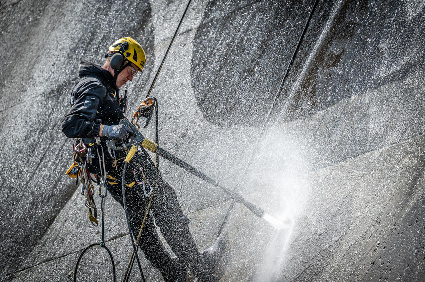 Seilzugangstechniker und Vermessungstechniker arbeiten gemeinsam mit Künstler Klaus Dauven an der präzisen Umsetzung des Reverse-Graffiti-Kunstwerks. Gereinigt wird ausschließlich mit Wasser und Hochdruck – ohne chemische Zusätze.