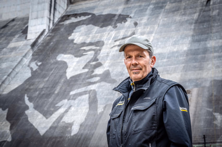 Durch das gezielte Entfernen der über Jahrzehnte entstandenen Patina aus Moosen und Flechten entsteht das monumentale Reverse-Graffiti-Motiv auf der Staumauer. Das Kunstwerk basiert ausschließlich auf dem Kontrast zwischen gereinigten und ungereinigten Flächen.