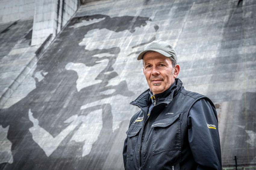 Durch das gezielte Entfernen der über Jahrzehnte entstandenen Patina aus Moosen und Flechten entsteht das monumentale Reverse-Graffiti-Motiv auf der Staumauer. Das Kunstwerk basiert ausschließlich auf dem Kontrast zwischen gereinigten und ungereinigten Flächen.