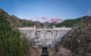 Reverse-Graffiti-Kunstwerk auf der 56 Meter hohen und 228 Meter breiten Staumauer des Matsudagawa-Staudamms in Ashikaga (Japan). Künstler Klaus Dauven gestaltet das monumentale Motiv gemeinsam mit Kärcher ausschließlich durch gezielte Hochdruckreinigung.