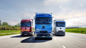 Blauer Mercedes-Benz eActros 600 fährt zwischen einem roten und einem weißen Mercedes-Benz Lkw auf einer Teststrecke.
