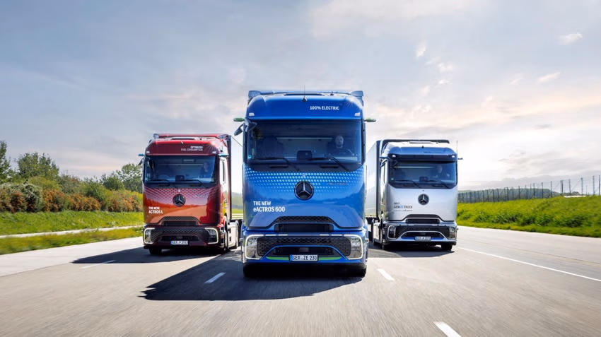Blauer Mercedes-Benz eActros 600 fährt zwischen einem roten und einem weißen Mercedes-Benz Lkw auf einer Teststrecke.