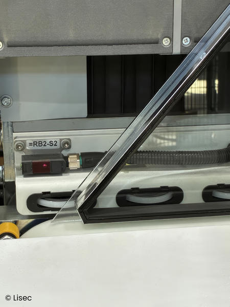 Schwarzer Abstandhalter im Eckbereich einer Glasscheibe an der Produktionslinie.