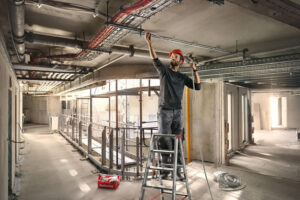 Monteur befestigt Leitungsinstallationen an einer Betondecke auf einer Baustelle