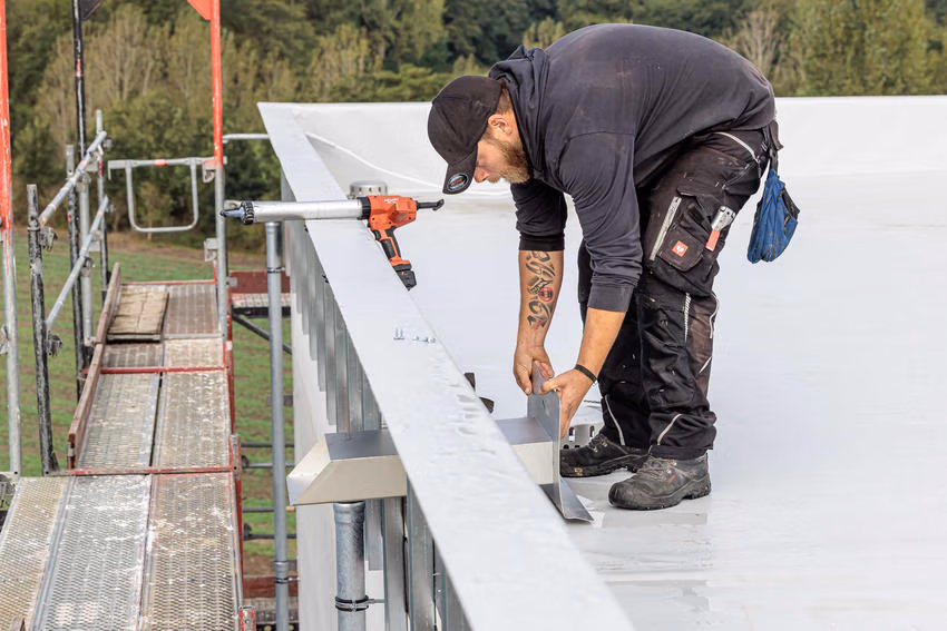 Dachdecker bei der Montage eines Rechteckspeiers am Dachrand