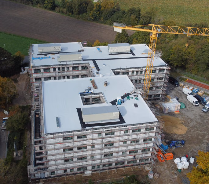 Luftaufnahme des Schulneubaus mit Flachdächern und Baustellenkran