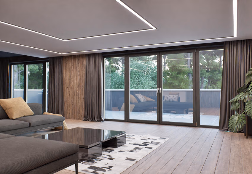 Wohnzimmer mit grauem Sofa und bodentiefer Fenster- und Türanlage zur Terrasse