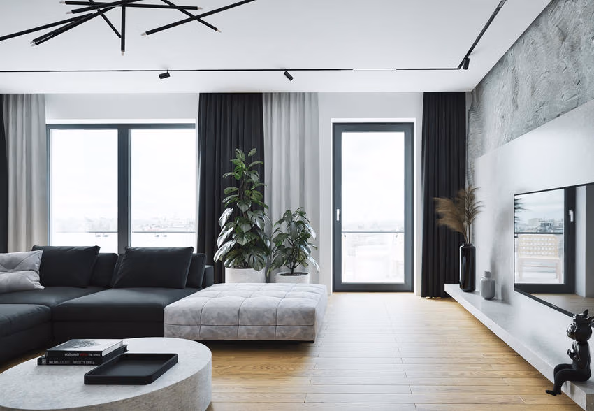 Wohnzimmer mit dunklen bodentiefen Fensterrahmen, grauem Sofa und Blick auf benachbarte Gebäude.