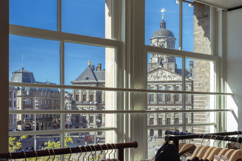Blick durch weiße Fensterrahmen auf den Königlichen Palast in Amsterdam, davor Kleiderständer.