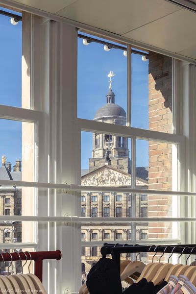 Fenster im Verkaufsbereich mit Blick auf den Palastturm und Kleiderbügeln im Vordergrund