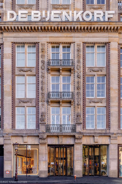 Eingang des Kaufhauses De Bijenkorf unter drei Fensterachsen, Balkonen und großem Schriftzug.