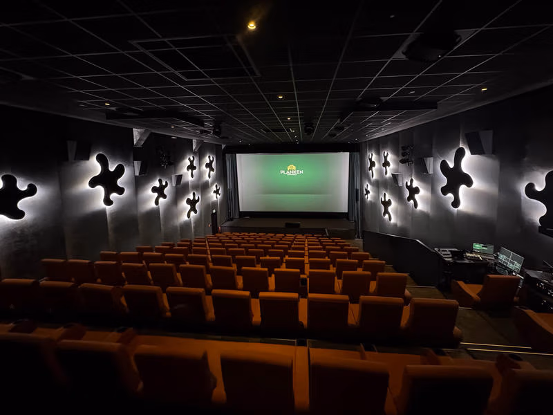 Blick über orangefarbene Kinositze zur Leinwand in einem Saal der Planken Lichtspiele Mannheim. 