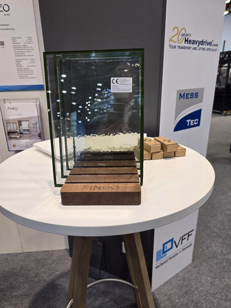 FINEO-Vakuumglasmuster in Holzhaltern auf einem runden Ausstellungstisch.