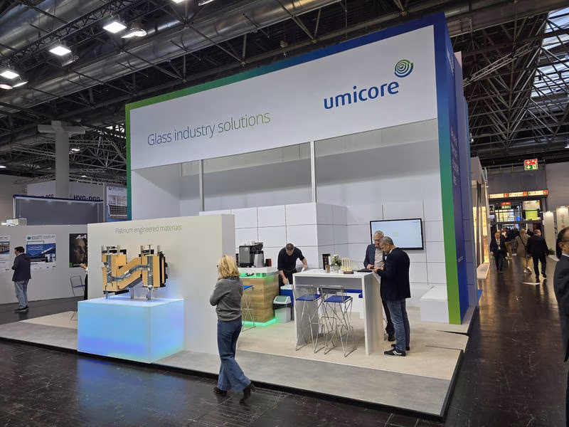 Umicore-Messestand mit der Aufschrift Glass industry solutions und einem ausgestellten Anlagenmodell.