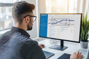 Person am Schreibtisch vor einem Monitor mit Airflow-Bedienoberfläche und Anlagenschema.