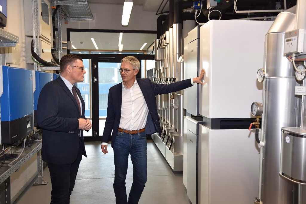 Bildunterschrift: Der Bundestagsabgeordnete Wilhelm Gebhard (links) im Gespräch mit Stiebel Eltron-Geschäftsführer Dr. Kai Schiefelbein an den beiden Wärmepumpen, die im Energy Campus, dem Schulungs- und Kommunikationszentrum des Unternehmens, für Heizung, Kühlung und Warmwasserbereitung sorgen. Bild: Stiebel Eltron